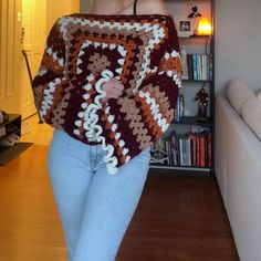 a woman is walking in the living room wearing a crocheted granny's sweater