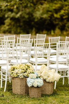 white chairs and wicker baskets filled with hydrangeas are set up for an outdoor ceremony