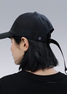 a woman wearing a black hat with a ponytail under her chin and ear piercings