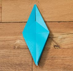 a blue origami object sitting on top of a wooden floor