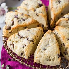 a cake with chocolate chips on it sitting on top of a purple cloth next to flowers