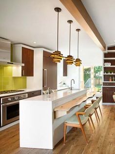 an open kitchen and dining room with wood flooring, white countertops and wooden chairs