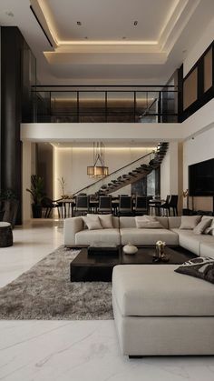 a large living room with white couches and black tables in front of a staircase