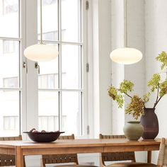 a wooden table with two vases on top of it next to a bowl of fruit