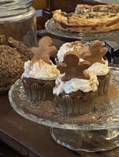 some cupcakes are sitting on glass plates with frosting and gingerbread decorations