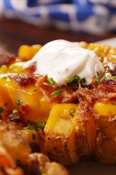 a close up of a plate of food with potatoes and sour cream on the top