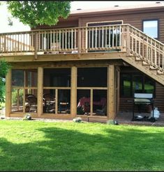 a wooden deck with sliding glass doors and railings on the side of a house