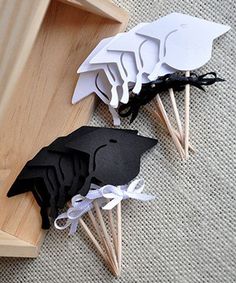 four black and white paper birds on wooden sticks in front of a wood box with handles