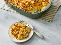 a casserole dish with cheese and vegetables on a plate next to a fork