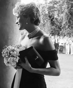 a black and white photo of a woman in a dress holding a bouquet of flowers