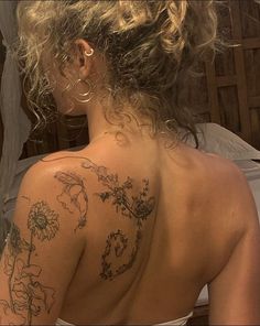 the back of a woman's neck with tattoos on it and flowers all over her body