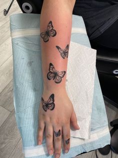 a person with a tattoo on their arm and butterfly tattoos on the wrist, sitting in a chair