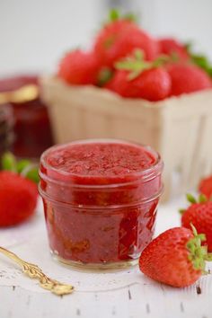 a jar of strawberry jam next to some strawberries