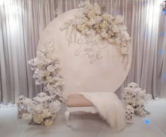 a white chair sitting in front of a backdrop with flowers