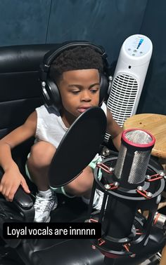 a young boy sitting in front of a microphone and headphones on top of a chair