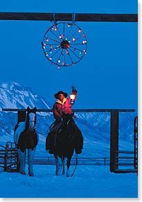 two people are riding horses in the snow at night with a ferris wheel behind them