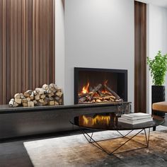 a living room with a fire place in the center and wood logs on the floor