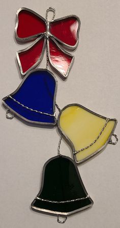 three different colored bell ornaments on a white surface