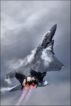 a fighter jet flying through a cloudy sky