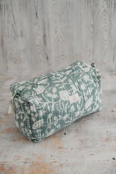 a green and white bag sitting on top of a wooden floor next to a wall