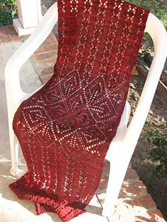 a red crocheted blanket sitting on top of a white chair