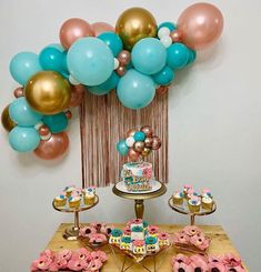 a table topped with cake and cupcakes next to balloons