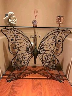 an iron butterfly table with glass top in the corner of a living room or entryway