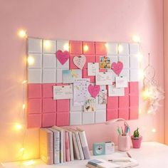 a white desk topped with lots of books next to a wall covered in pink and white tiles