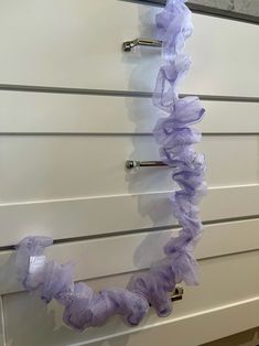 a white dresser topped with drawers covered in purple scrunffles on it's sides