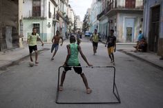 a group of young men playing soccer in the middle of an alleyway with buildings on both sides