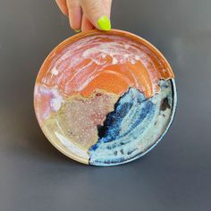 a hand holding a small bowl with different colors on it