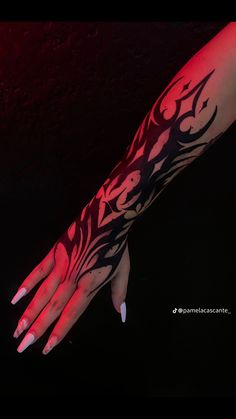 a woman's arm with black and red tattoos on it, in the dark