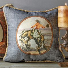 two decorative pillows on a shelf with a candle