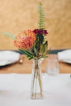 a vase filled with flowers sitting on top of a table next to plates and utensils