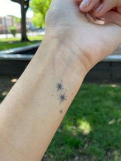 a person holding their arm up in the air with a star tattoo on it's wrist