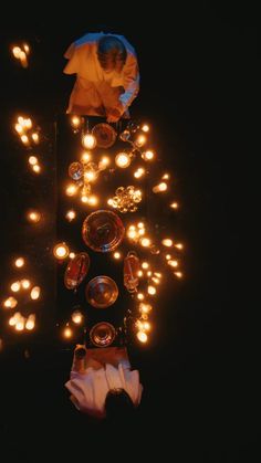 a table topped with lots of lit candles and plates next to each other on top of a black surface