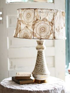 a lamp that is on top of a table next to a book and a window