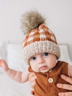 a baby wearing a knitted hat with a pom