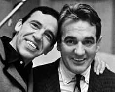 black and white photograph of two men in suits smiling at the camera, one holding his arm around the other's shoulder