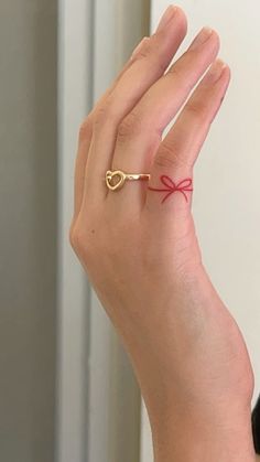 a woman's hand wearing a gold ring with a red string tied around it