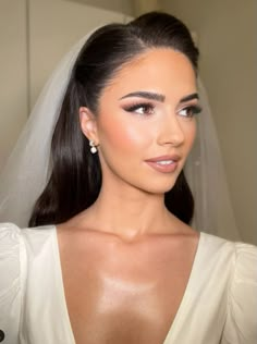 a woman in a wedding dress with her hair up and wearing a veil over her head