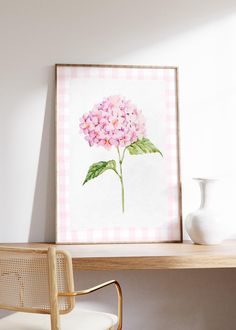 a pink hydrangea flower sitting on top of a wooden table next to a white vase