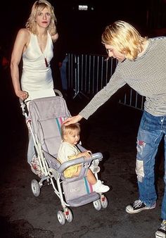 a woman pushing a baby in a stroller with another woman standing next to her