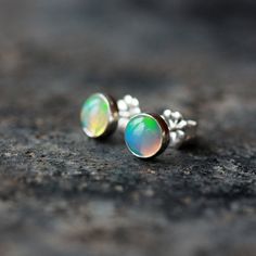 Beautiful, iridescent Ethiopian opal gems are the stars of these elegant earrings. Set entirely in sterling silver, the genuine opals measure 6mm in diameter--these are not manmade or simulated opals. Each real opal is entirely unique, with its own play of color and light. I match the two opals so they compliment each other, but they will never be identical. These are real, natural opal gemstones, not manmade or fake opals. The studs come with large, matching sterling silver push backs. **opals Hypoallergenic Sterling Silver Iridescent Jewelry, Hypoallergenic Iridescent Sterling Silver Jewelry, Silver Opal Earrings For Anniversary, Anniversary Silver Opal Earrings, Opal Gemstone Earrings For Anniversary, Iridescent Opal Jewelry For Anniversary, Silver Ethiopian Opal Round Jewelry, Iridescent Opal Cabochon Jewelry, Iridescent Round Opal Jewelry