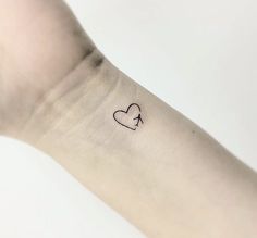 a small heart tattoo on the left inner arm, with an arrow in the middle