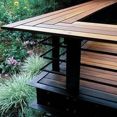 a wooden bench sitting on top of a lush green hillside next to flowers and trees