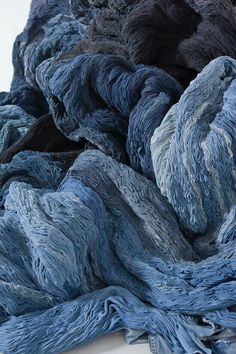 blue and grey yarn is piled up in the shape of an abstract rock formation on a white background