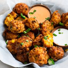 a basket filled with fried food next to a small bowl of ranch dressing on the side