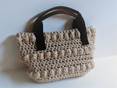 a crocheted handbag hanging on a wall with the word pattern written below it