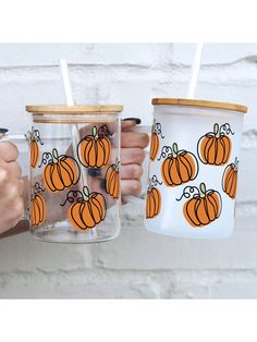 two people holding cups with pumpkins on them